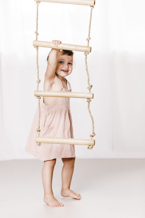Ein kleines Maedchen fotografiert mit einer Strickleiter im Fotostudio